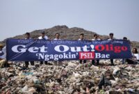 Aktivis Lingkungan Hidup Kalung membentangkan spanduk Get Out Oligo di TPA Rawakucing. Foto: ist